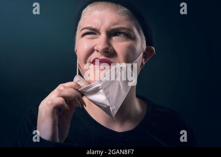 ritratto di una giovane donna infastidita dalla sua maschera protettiva corona Foto Stock