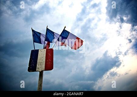 Bandiere francesi che sventolano orgogliosamente contro un cielo drammatico al crepuscolo, catturando l'essenza dell'orgoglio e del patrimonio nazionale Foto Stock