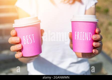 Persona che tiene due tazze monouso rosa con il concetto migliore amico. Foto Stock