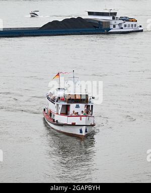 Wiesbaden Schierstein, Germania. 27 luglio 2021. Mentre una barca da diporto passa davanti a una nave da carico sul Reno, un'escursione in barca si trasforma nel porto di Schierstein. Poiché Corona ha reso più difficile viaggiare, è diventato sempre più affollato sui fiumi in estate. Nautica sportiva, moto d'acqua e stand-up paddle (SUP) in particolare sono diventati sempre più popolari per anni. E non solo sul Reno e meno, ma anche sugli altri fiumi. (To dpa 'Trubel und Trouble auf Rhein und Main - Jetski-Fahrer in der Kritik') Credit: Arne Dedert/dpa/Alamy Live News Foto Stock