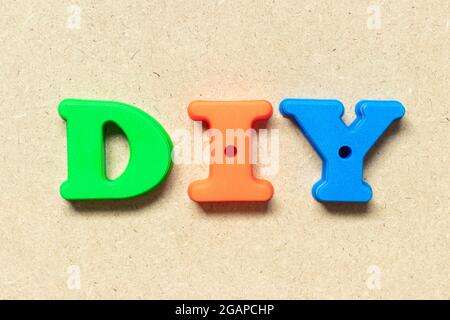 Lettera alfabetica in plastica in parole DIY (abbreviazione di Do IT Yourself) su sfondo di legno Foto Stock