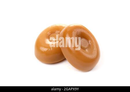 Due caramelle al caramello su sfondo bianco da vicino. Foto Stock