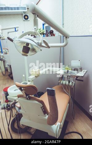 Servizi odontoiatrici. Sedia del dentista e altri accessori utilizzati dai dentisti in una stanza medica. Effetto filtro su pellicola vintage. Foto Stock