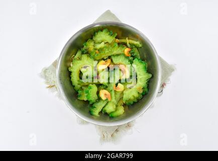 Sud-est asiatico, Myanmar o indiano tradizionale zucca amara (Karela) e piccoli gamberi curry in piatto d'acciaio. Isolato su bianco. Vista dall'alto Foto Stock