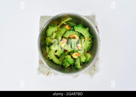 Sud-est asiatico, Myanmar o indiano tradizionale zucca amara (Karela) e piccoli gamberi curry in piatto d'acciaio. Isolato su bianco. Vista dall'alto Foto Stock