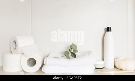 Lavabo in bagno bianco, ripiano con accessori da bagno. Concetto di pulizia dell'hotel. Concetto domestico. Panno, flacone di shampoo, crema per il corpo, punta bianca Foto Stock