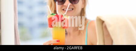 Giovane donna in costume da bagno e occhiali da sole che beve cocktail sulla vacanza closeup Foto Stock