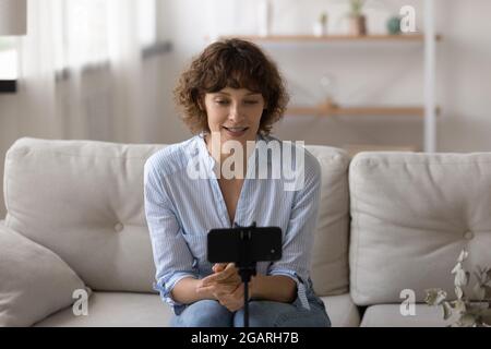 Piacevole giovane attraente donna che registra video sul cellulare. Foto Stock