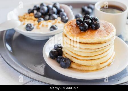 Deliziosa e sana colazione a base di frittelle con mirtilli, muesli e una tazza di caffè Foto Stock
