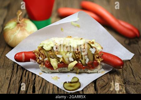 Hot dog in stile danese con tradizionale salsiccia rossa su rustico sfondo di legno Foto Stock