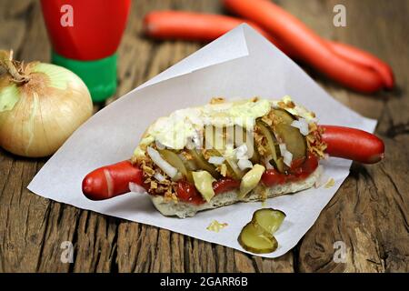 Hot dog in stile danese con tradizionale salsiccia rossa su rustico sfondo di legno Foto Stock