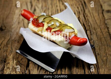 Hot dog in stile danese con tradizionale salsiccia rossa su rustico sfondo di legno Foto Stock