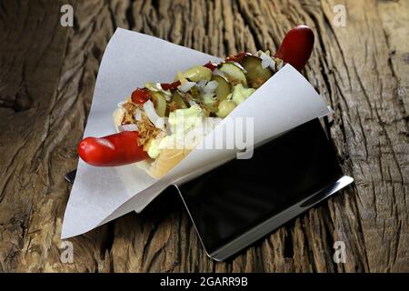 Hot dog in stile danese con tradizionale salsiccia rossa su rustico sfondo di legno Foto Stock