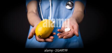 Una ragazza allegra dottore in tuta medica e con uno stetoscopio tiene un limone Foto Stock