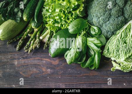 Verdure fresche verdi avocado, broccoli, spinaci, cetrioli, cavolo, lattuga su un tavolo di legno. Foto Stock