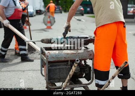 Generatore di benzina di elettricità. Alimentazione all'utensile elettrico. Generatore sulla strada per la riparazione stradale. Foto Stock