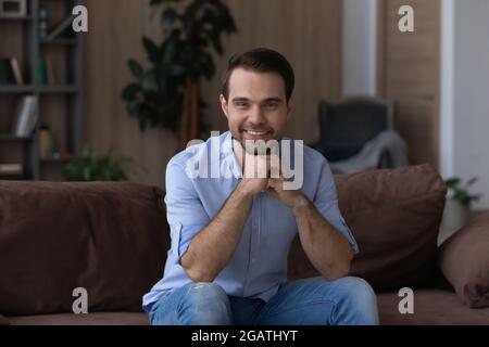 Un giovane felice si siede sul divano nel moderno soggiorno Foto Stock