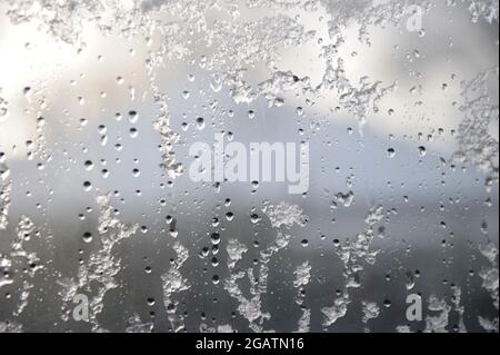 Neve, ghiaccio e goccioline di pioggia scongelamento parziale su una finestra in inverno - immagine di sfondo per la funzione invernale Foto Stock