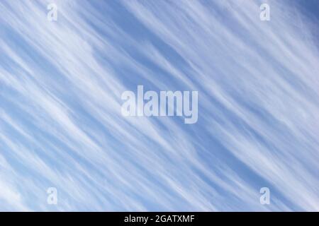 Nuvole di cirrus bianco sotto forma di strisce diagonali sullo sfondo blu cielo. Foto Stock