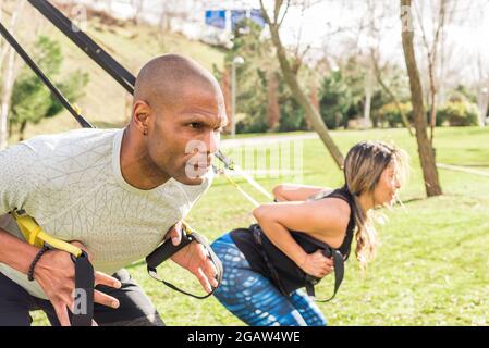 I partner atletici che fanno esercizi di schiena squatting con trx fitness Straps. Foto Stock