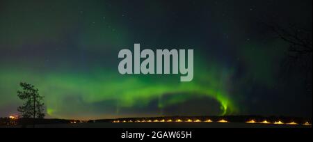 Un panorama multicolore Aurora borealis sul cielo stellato notturno sopra una città. Aurora Borealis sulle isole dei laghi svedesi. Svezia settentrionale. Wintertime st Foto Stock