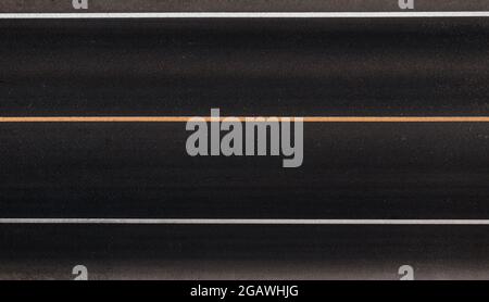 Segnaletica stradale dell'autostrada. Struttura di asfalto con linee di divisione. Vista dall'alto. Linea di divisione bianca e linea gialla temporanea. La consistenza di asfalto scuro pulito. Foto Stock