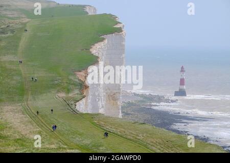Camminatori sulla South Downs Way passando il faro a Beachy Head, East Sussex, UK Foto Stock