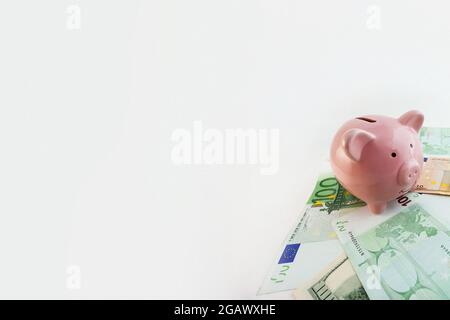 Panorama Pig a forma di banca piggy, banconote in euro e dollari USA su sfondo bianco isolato Foto Stock