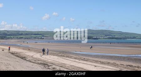 Gli escursionisti di cani su Ayr Beach guardando verso i capi di Ayr, Ayrshire, Scozia, Regno Unito quando la marea è fuori Foto Stock