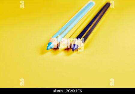 Tre matite di legno colorate su sfondo giallo Foto Stock