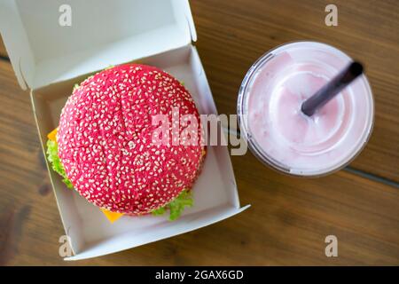 Panino di hamburger rosa senza glutine di barbabietole con hamburger vegetariano, con frullato rosa. Hamburger sano alternativo. Cibo alla moda. Vista dall'alto. Foto Stock