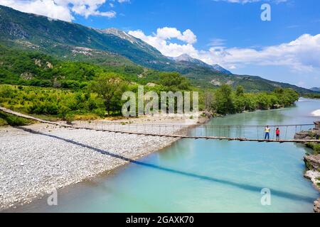 Madre e figlio in vacanza attraversando vecchio ponte sospeso sul bellissimo fiume Vjosa, vicino a Çarçovë, montagne Nemërçka, quartiere Gjirokastra, albania Foto Stock