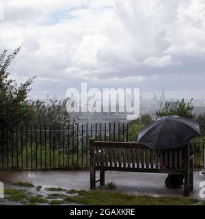 30/07/2021. Londra, Regno Unito. I membri del pubblico si affacciano sullo skyline di Londra durante una tempesta di pioggia a Greenwich. Park nel sud-est di Londra. Foto Stock