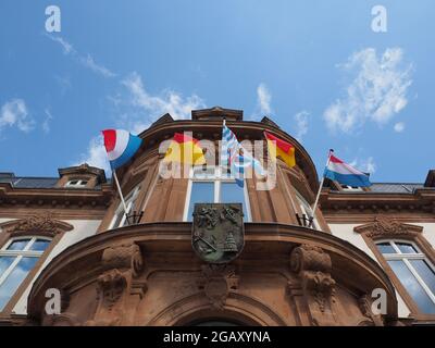 Bandiere sulla facciata anteriore del municipio di Wiltz in Lussemburgo con un cielo blu Foto Stock