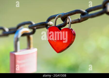Lucchetto rosso a forma di cuore appeso su una catena con inciso il segno dell'infinito. Foto Stock