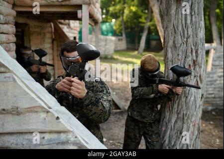 Giocatori di paintball in uniforme spara con le pistole Foto Stock