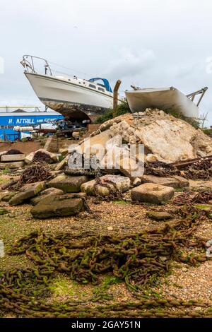 barche e barche in un vecchio cantiere sull'isola di wight a bembridge a bassa marea con vecchie catene sulla spiaggia. Foto Stock