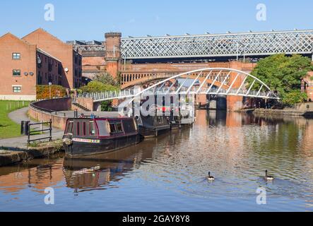 Vista dall'alzaia di barche strette dal ponte pedonale Merchants' Bridge sul canale Bridgewater e viadotto ferroviario, Castleford Basin, Manchester, Inghilterra Foto Stock