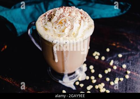 White Chocolate latte con panna montata e cacao in polvere: Una bevanda a base di caffè dolce fatta con cioccolato bianco e panna montata Foto Stock