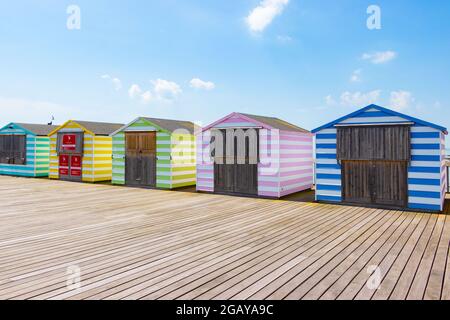 Capanne da spiaggia a strisce di caramelle pastello sul molo di Hastings, East Sussex Foto Stock