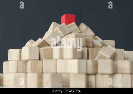 Piramide di cubetti beige sulla parte superiore con un solo rosso sul tavolo Foto Stock