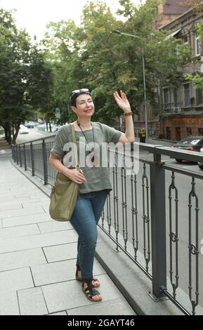 Una bella donna di mezza età che cammina per la città. Le donne di affari gradiscono camminare intorno alla città e pensare al loro commercio. Foto Stock