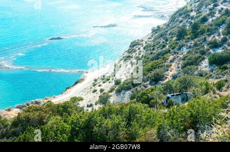 L'auto si è schiantata cadde da una scogliera a una riva. Scenario di incidente in idilliaco paesaggio mediterraneo con spiaggia di mare Foto Stock