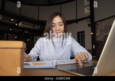 Intelligente bella donna intelligente asiatico pensiero di serie informazioni di studio positivo riassunto e business script saggio di fronte al computer portatile a. Foto Stock