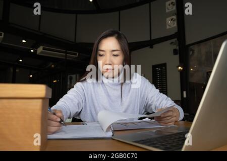 Intelligente bella donna intelligente asiatico pensiero di serie informazioni di studio positivo riassunto e business script saggio di fronte al computer portatile a. Foto Stock