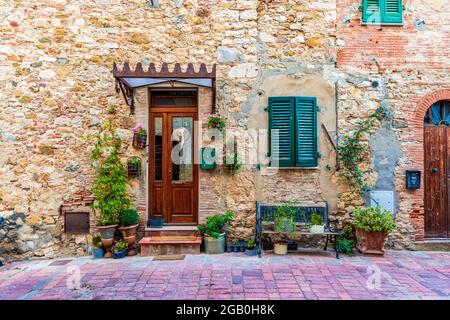Esterno di un edificio con cesti pendenti e fiori in un vicolo del borgo medievale di Suvereto, provincia di Livorno, Toscana, Italia. Foto Stock