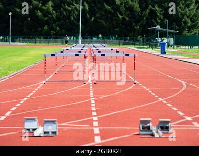 Ostacoli sulla corsia sprint con blocchi di partenza su sfondo sfocato. Stadio con due percorsi di allenamento per gli ostacoli.