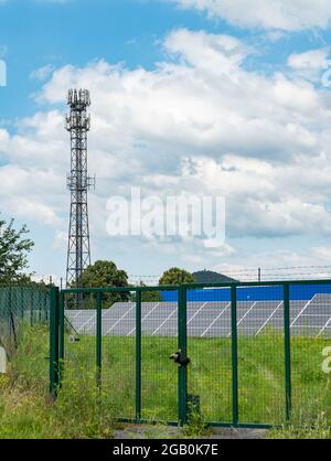 Centrale solare privata dietro la recinzione. Celle solari o pannelli solari in un campo di centrale solare. Le batterie assorbono la luce solare dal sole Foto Stock