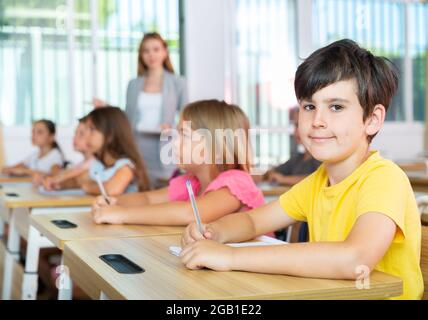 Sorridente diligente presteen ragazzo che studia con compagni di classe Foto Stock