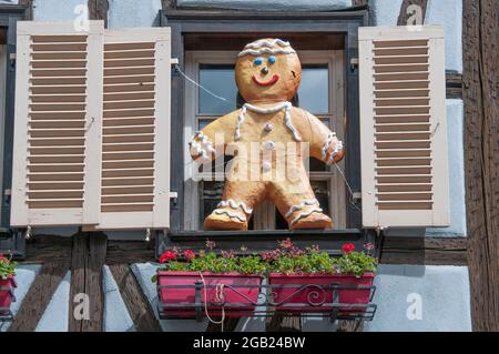 Una scultura di un uomo di pan di zenzero, simile a un bambino, adorna la finestra di una casa a graticcio a Kaysersberg, una città sulla strada del vino dell'Alsazia, nella Francia orientale Foto Stock